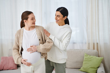 A pregnant woman sits on a sofa next to her trainer during parents courses, while another woman...
