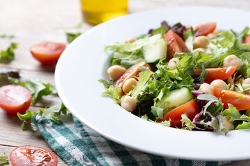 Healthy chickpea salad with tomato,lettuce and cucumber on wooden table