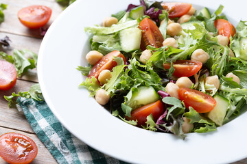 Healthy chickpea salad with tomato,lettuce and cucumber on wooden table