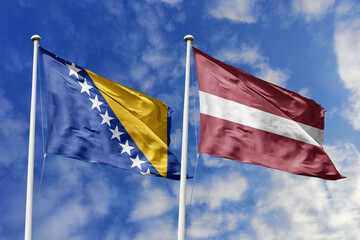 3D illustration. Bosnia and Herzegovina and Latvia flags waving in the sky. High detailed waving flag. 3D render. Flags fluttered in the cloudy sky, symbolizing diplomatic relations.