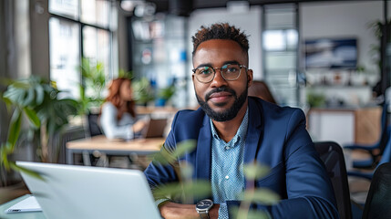 Fototapeta premium young african american businessman in eyeglasses using laptop in office