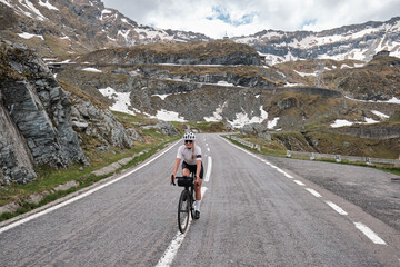 Woman cyclist riding a road bike with a view of the mountains. Sport motivation.Female cyclist wearing a cycling kit and helmet. Carpathian Mountains, Transfăgărășan road in Romania.