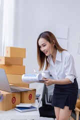 Portrait of Starting small businesses SME owners female entrepreneurs working on receipt box and check online orders to prepare to pack the boxes, sell to customers, SME business ideas online.
