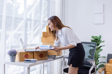 Portrait of Starting small businesses SME owners female entrepreneurs working on receipt box and check online orders to prepare to pack the boxes, sell to customers, SME business ideas online.
