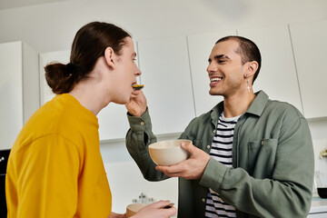 A young gay couple enjoys a meal together in their modern apartment, sharing a moment of intimate connection.