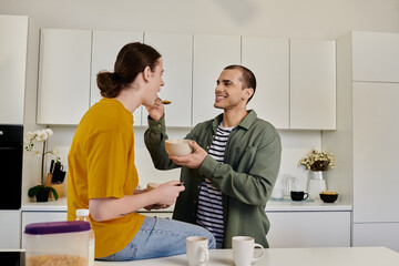 A young gay couple enjoys a light breakfast together in their modern apartment kitchen.