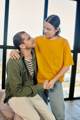 A young gay couple enjoys a quiet moment together in their modern apartment.