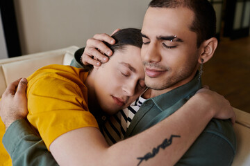 Fototapeta premium A young gay couple cuddles on a couch in their apartment, showcasing intimacy and comfort.