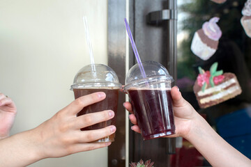 Two hands holding a plastic glasses with a drink