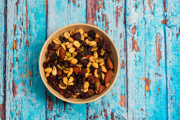 Mix of nuts and dried fruits in a wooden bowl on a wooden background, student mix of nuts and dried...