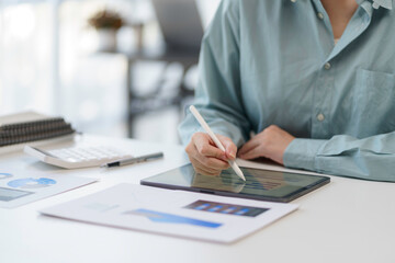 Person using a tablet with a stylus in a modern office environment, working on digital documents...