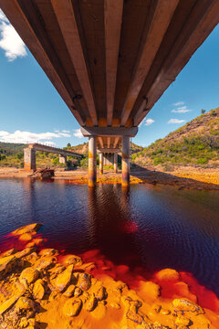 Vibrant Riotinto river scene under a concrete bridge