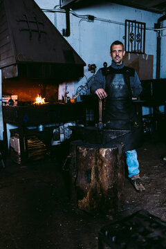 Confident blacksmith standing in a traditional workshop