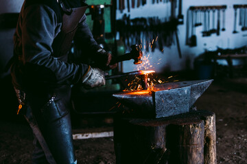 Blacksmith shaping metal on an anvil with sparks flying