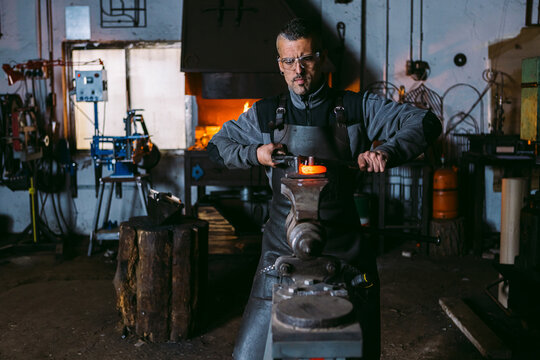 Blacksmith working hot metal at anvil in workshop