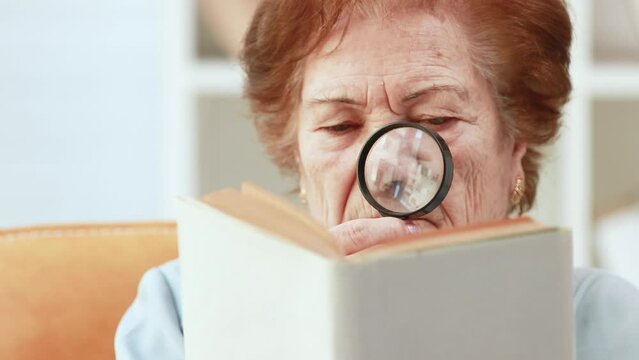senior woman with presbyopia reading with magnifying glass with tired eyesight