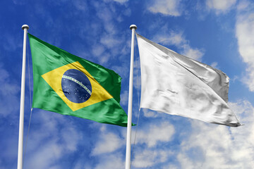 A Brazilian flag beside a white flag, a metaphor for unity and peace, waves against a blue sky,...