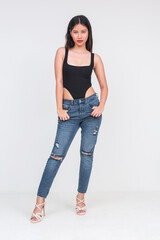 Front view of a fierce looking young asian woman of ideal height and figure in a black bodysuit and...