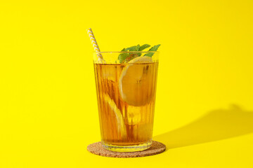 Cold tea with orange slices and mint leaves on a yellow background