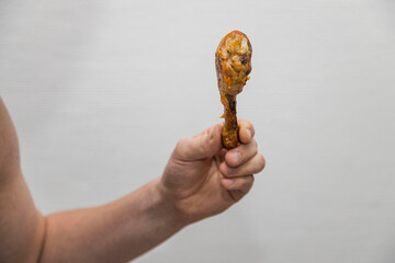 Caucasian man holds a crispy cooked a chicken leg