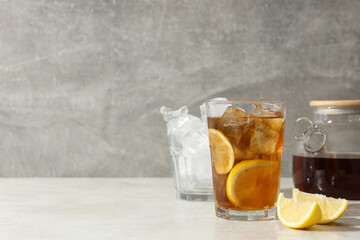 A glass of cold tea with ice and an orange