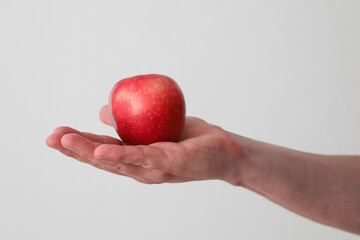 A Caucasian man holds a red apple in a hand - white background