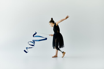 A young girl with a prosthetic leg performs a graceful gymnastics routine with a ribbon.