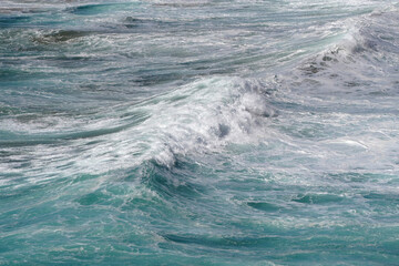 Wellenformationen mit Gischt an der Küste mit Schaumkronen