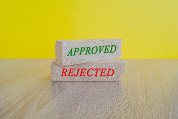 Concept words approved and rejected on brick blocks. Beautiful wooden table, yellow background. Business concept.