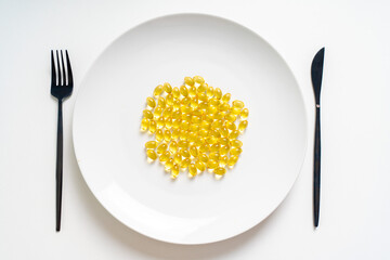 Lots of pills, omega-3 vitamins in a white plate, fork and knife on a white background. Diet and...