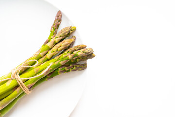 A pile of raw garden asparagus with isolated shade. Fresh green spring vegetables on a white background. Edible asparagus sprouts, top view