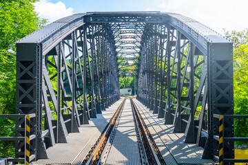 A historic railway bridge in Rataje is captured on a bright, sunny day. The bridge is surrounded by...