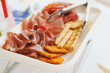 A plate with cold cuts and breadsticks. A delicious jerky appetizer.