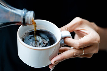 Pouring dark beverage into white cup