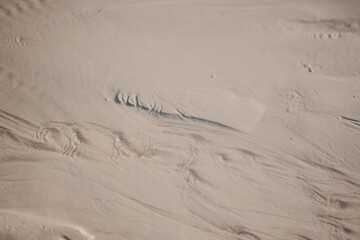 White sandy texture on a beach background with ripples and waves.