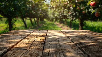 Fototapeta premium The tabletop of an empty wooden table against a background of fruit trees. Use a template layout to demonstrate your design, a banner to advertise the product. Natural background.