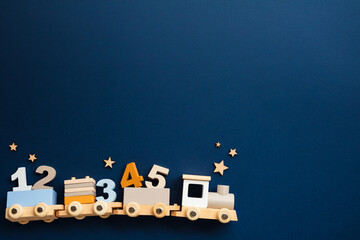 Wooden toy train locomotive with numbers on dark blue background. Baby early education, learn to count concept