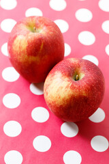 Ripe organic red apple on polka dot table background.