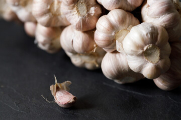 Ripe organic garlic clove and bulb on black stone background.  Close-up. Selective focus.