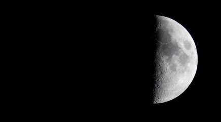 Half moon during the first quarter phase isolated against a black sky.