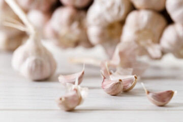 Ripe organic garlic clove and bulb on white wooden background.  Close-up. Selective focus.