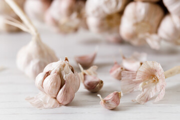 Ripe organic garlic clove and bulb on white wooden background.  Close-up. Selective focus.