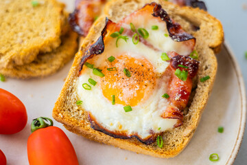Baked Bacon and Eggs in Bread on White Plate with Fresh Green Onion Close-Up