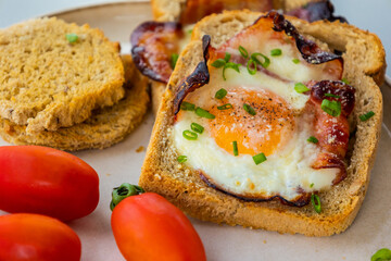 Baked Bacon and Eggs in Bread on White Plate with Fresh Green Onion Close-Up