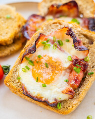 Baked Bacon and Eggs in Bread on White Plate with Fresh Green Onion Close-Up