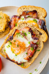  Baked Bacon and Eggs in Bread on White Plate with Fresh Green Onion Close-Up
