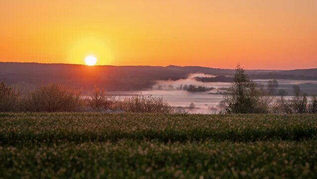 Beautiful HDR timelapse sunrise over a valley. Sun rising up over a river valley with thick morning fog, agricultural field on the foreground