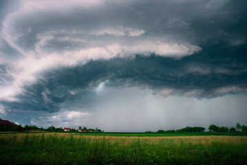 Beautiful and Amazing Ominous Supercell Thunderstorm Clouds over Green Fields in Summer