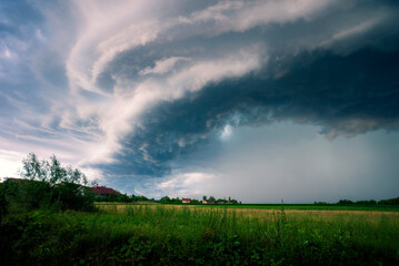 Beautiful and Amazing Ominous Supercell Thunderstorm Clouds over Green Fields in Summer
