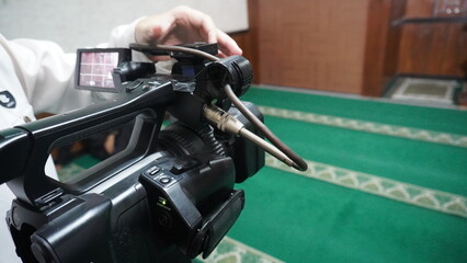 Someone is setting up the camera for the live broadcast, looking focused on the screen and...